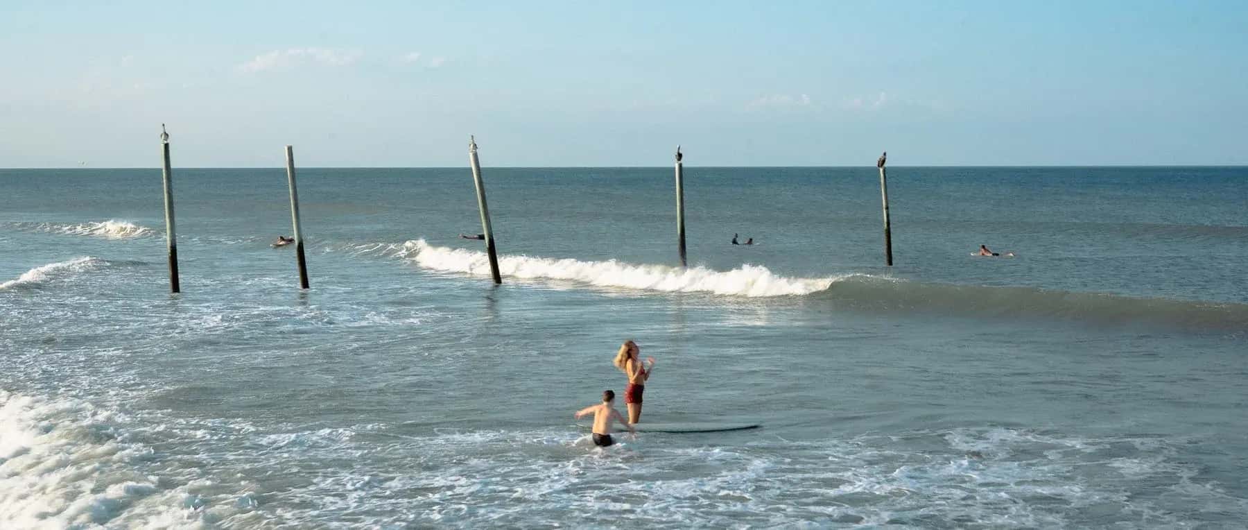 Surfers paddling out between the old pier pilings at New Smyrna Beach
