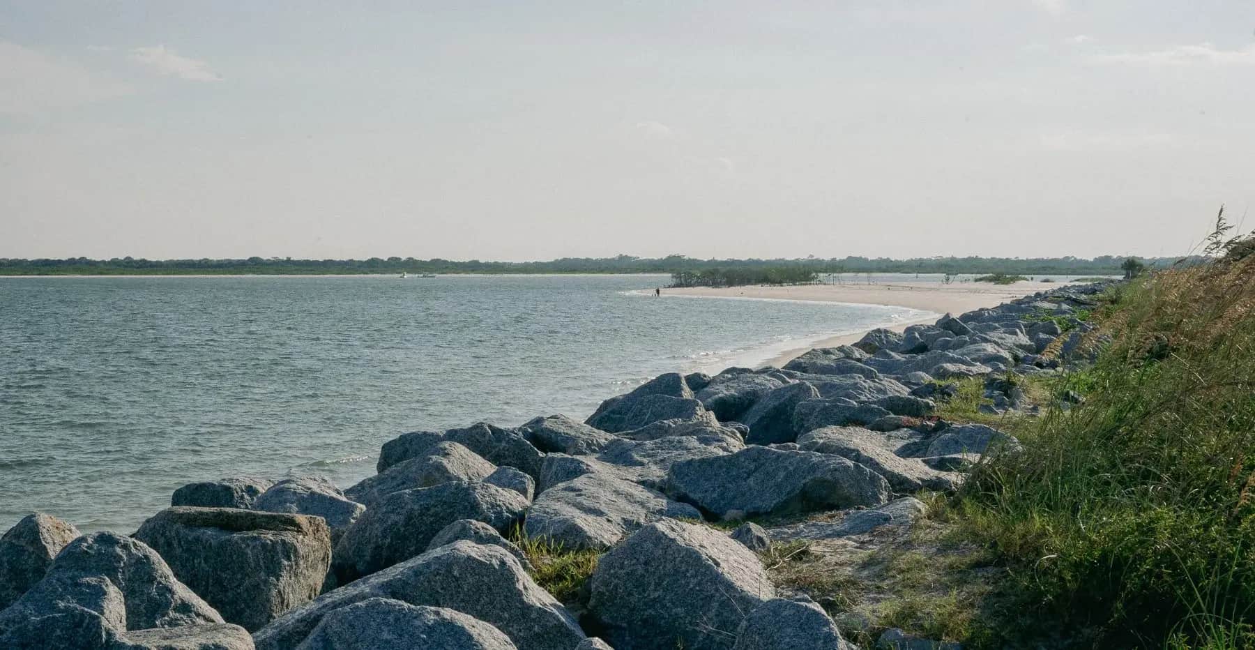 Rock jetty curving along the sand at the inlet, New Smyrna Beach